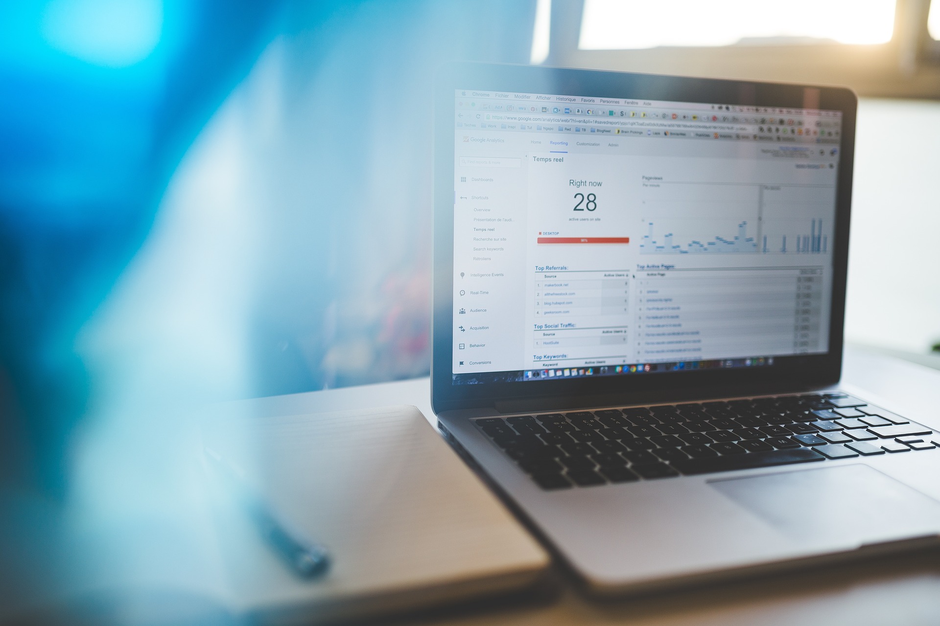 THIS IS IMAGE OF A LAPTOP ON A DESK DISPLAYING GOOGLE ANALYTICS OF WEBSITE TRAFFIC